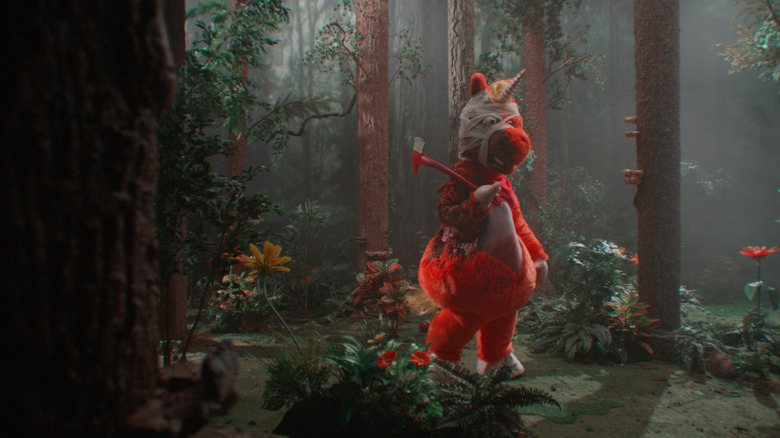 Buddy stands in the woods with an axe in Buddy