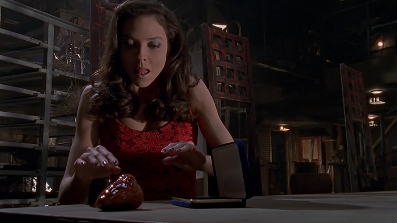 Juliet Landau as Drusilla on Buffy the Vampire Slayer, licking her lips as she reaches for a bloody heart on a table