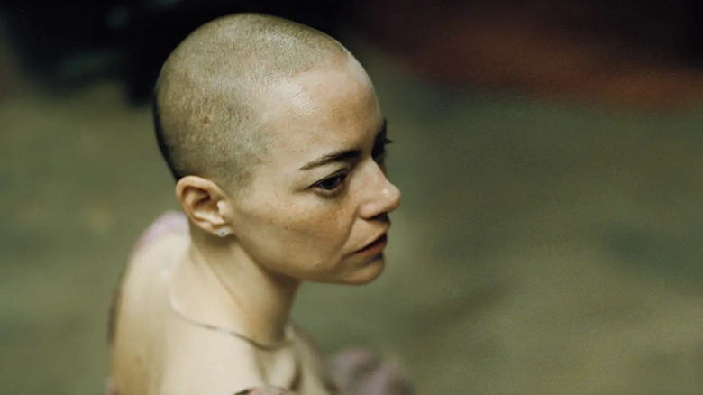 Bald Michelle looking over her shoulder in Bugonia