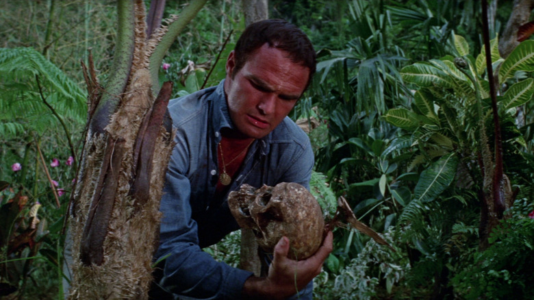 Burt Reynolds as Douglas Temple holding a skull in Skullduggery