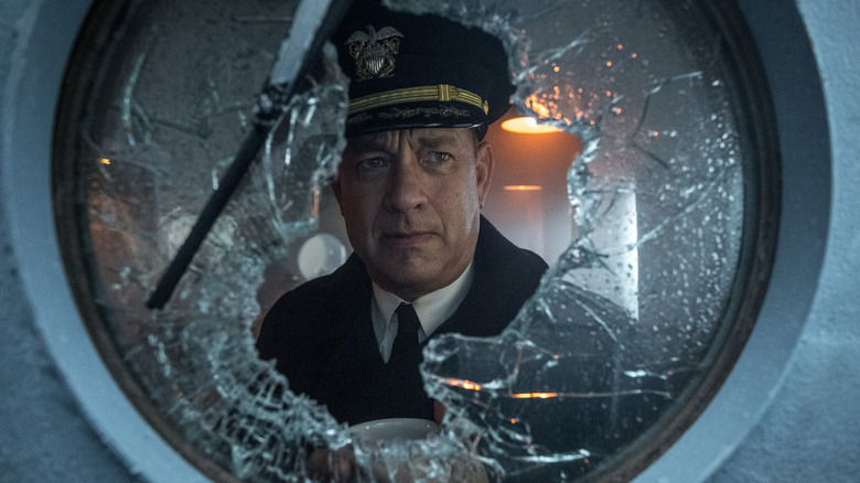 Tom Hanks as Naval Commander Ernie Krause looking worriedly out of a shattered porthole on his ship in Greyhound