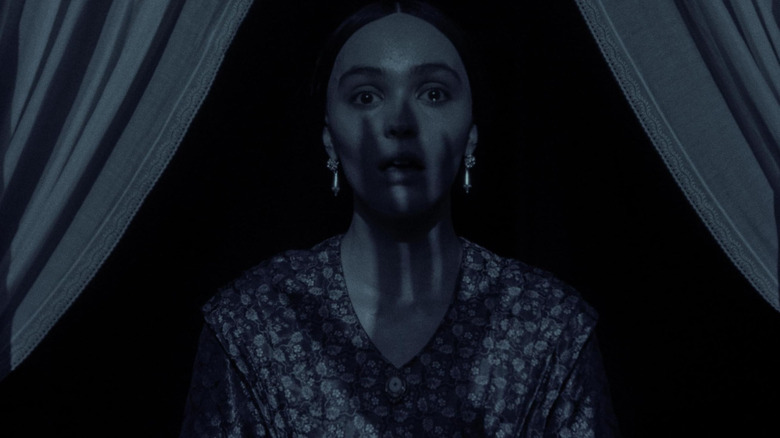 Lily-Rose Depp como Ellen Hunter com a sombra da mão do Conde Orlok no rosto em Nosferatu (2024)