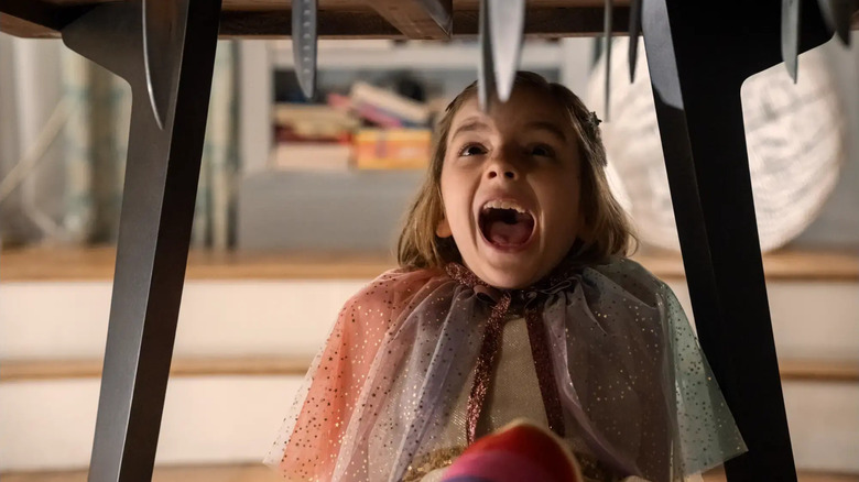 Arabella Olivia Clark as Bela screaming under a table with knives in it in Other Mommy