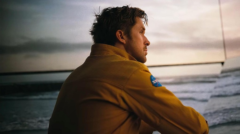 Ryan Gosling dans le rôle de Ryland assis dans sa veste de la NASA au bord de l'eau dans le projet Hail Mary