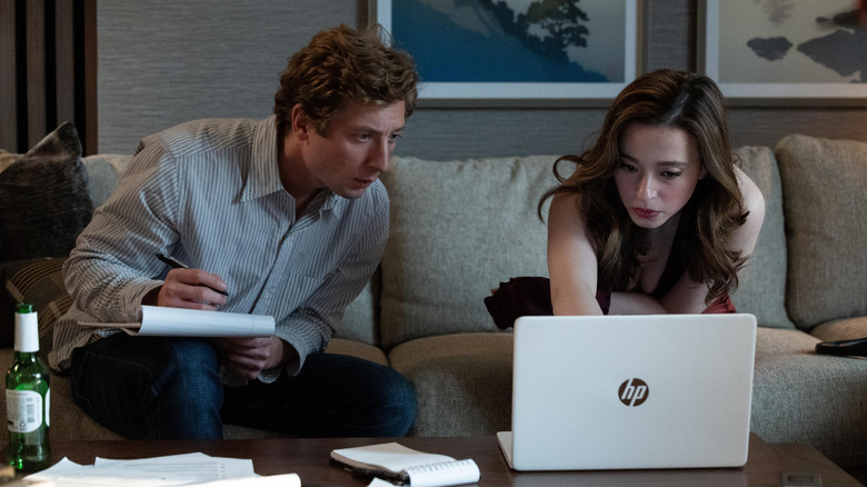 Jeremy Allen White as Jeff Horwitz sitting next to Mikey Madison as Frances Haugen on a couch looking at a laptop in The Social Reckoning