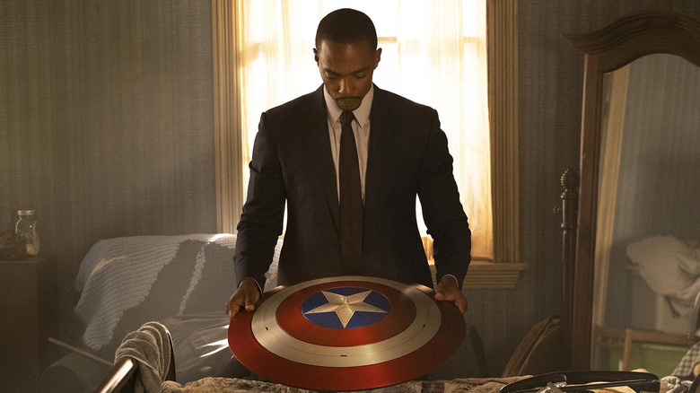 Falcon and the winter soldier: Sam Wilson holding the Shield Captain America in a business costume