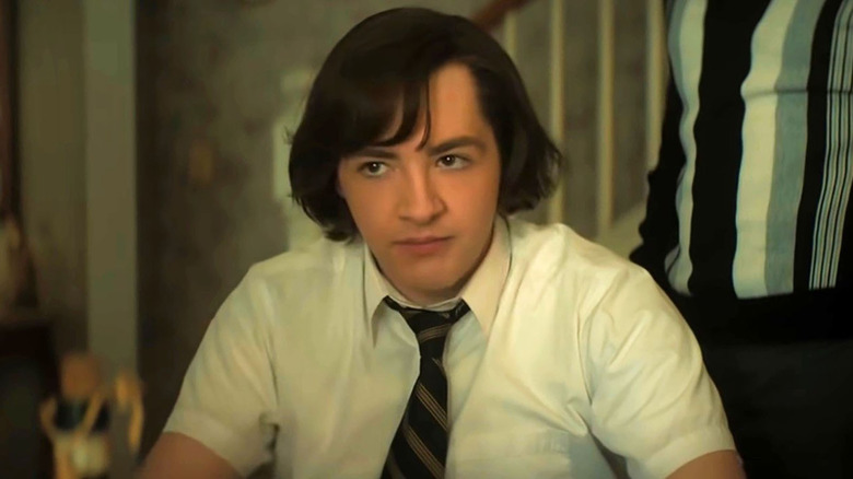 boy with long hair sitting in a short-sleeved button up shirt and tie