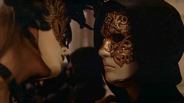 Tom Cruise's Dr Bill Harford wears a mask as he faces a masked woman in Eyes Wide Shut