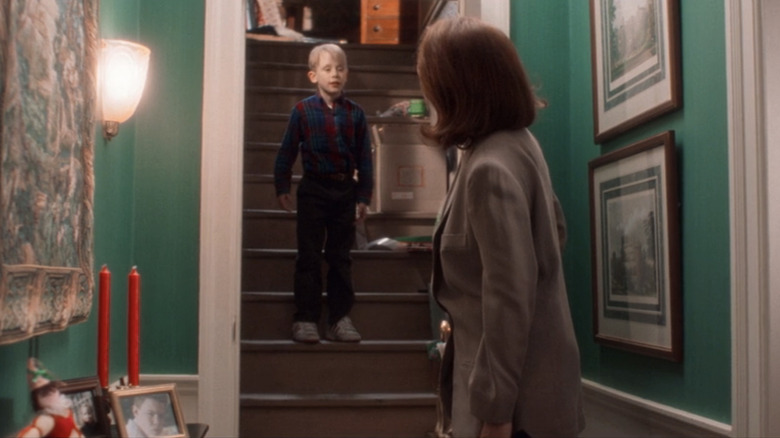 Catherine O'Hara's Kate McCallister opens the door to her attic as Macaulay Culkin's Kevin stands on the stairs in Home Alone