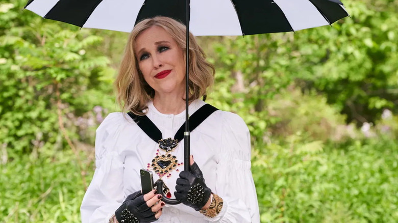 Moira souriante et tenant un parapluie sur Schitt's Creek