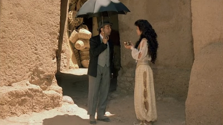 Gérard Jugnot's Jimmy Genius stands holding an umbrella opposite Catherine Zeta-Jones' Scheherazade  in Les 1001 Nuits