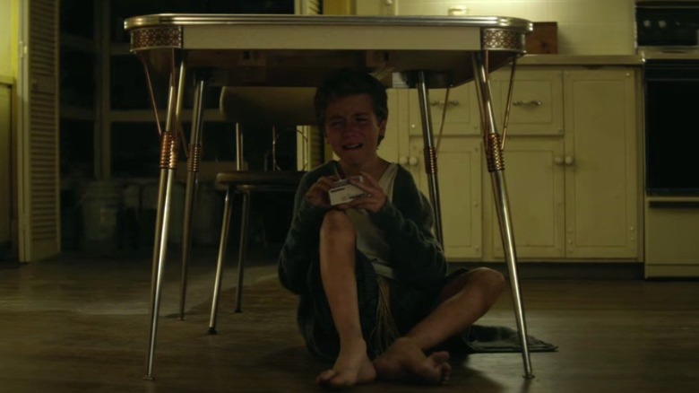Tim crying while sitting under a table