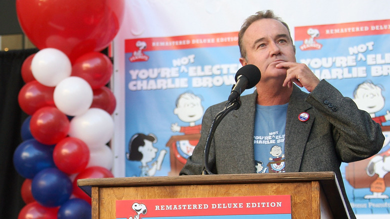 Peter Robbins surrounded by balloons with a thinking face on and a finger on his chin