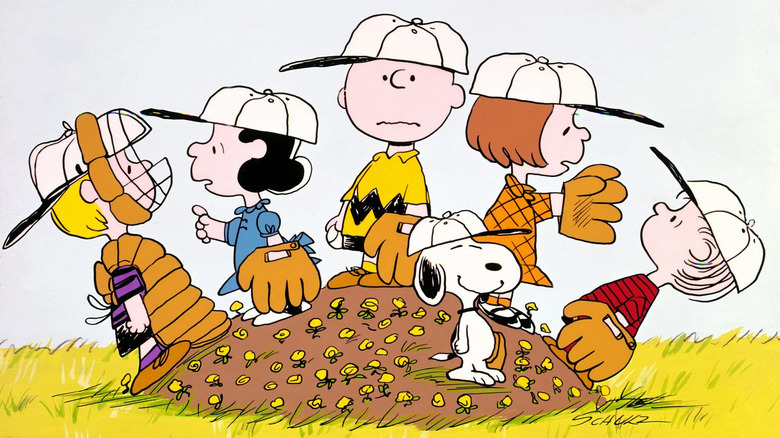 schroeder, lucy, charlie brown, peppermint patty, linus and charlie brown in baseball gear standing on the pitchers mound, which is covered in flowers