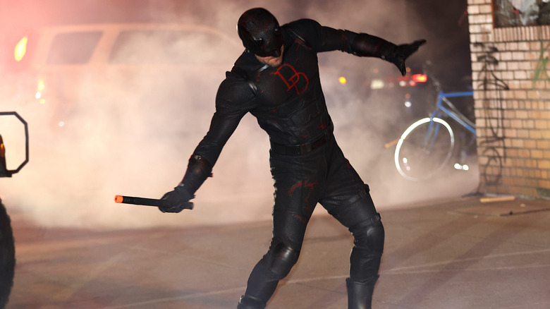 Charlie Cox as Daredevil in black costume swinging billy club