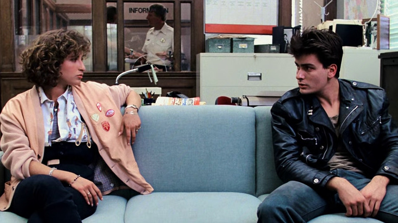 Jennifer Grey's Jeannie and Charlie Sheen's burnout character sitting on a couch in Ferris Bueller's Day Off