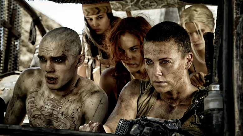 Furiosa drives the War Right with Nux and Immortan Joe's wives watching with concern in "Mad Max: Fury Road"