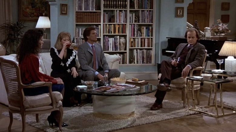 Bebe Neuwirth as Lilith Sternin, Shelley Long as Diane Chambers, Ted Danson as Sam Malone, and Kelsey Grammer as Frasier Crane sitting awkwardly in Cheers