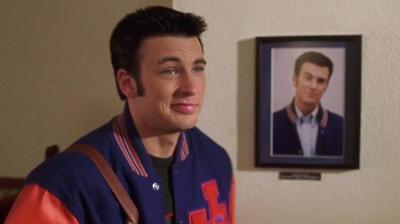 Chris Evans smirks in front of a framed photograph of him smirking as Jake Wyler in Not Another Teen Movie