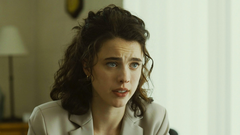 Margaret Qualley's Honey O'Donahue leans forward as she sits in an office in Honey Don't!