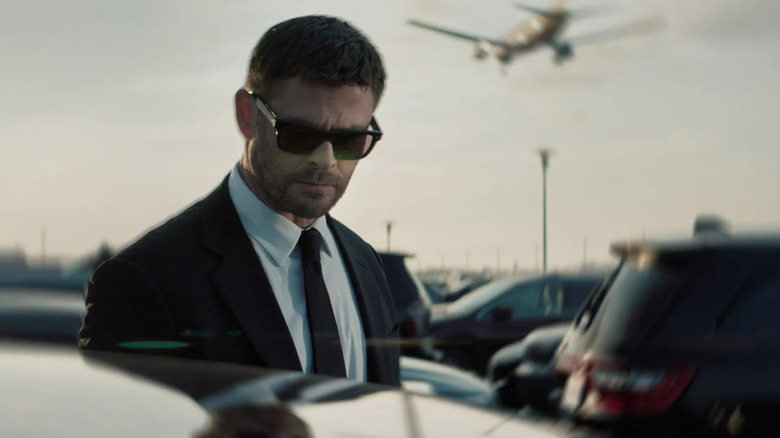 மைக் (கிறிஸ் ஹெம்ஸ்வொர்த்) கார் நிறுத்துமிடத்தில் நிற்கிறார் 