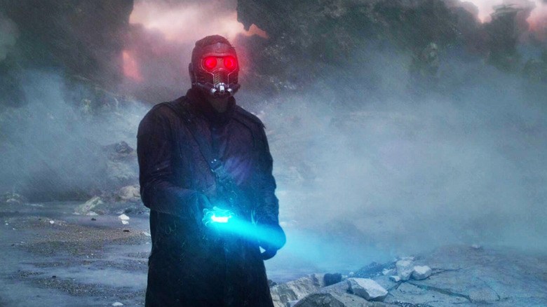 క్రిస్ ప్రాట్ యొక్క పీటర్ క్విల్/స్టార్-లార్డ్ గార్డియన్స్ ఆఫ్ ది గెలాక్సీలో ఫ్లాష్‌లైట్‌ని వెలిగిస్తూ బంజరు ప్రకృతి దృశ్యంలో నిలబడి ఉన్నాడు