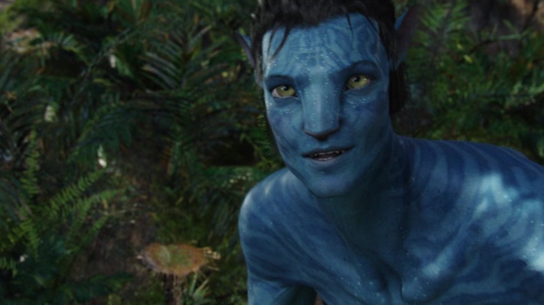 సామ్ వర్తింగ్టన్ యొక్క జేక్ సుల్లీ అవతార్‌లో ఆకుల మీద నిలబడి నవ్వుతున్నాడు