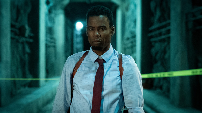 Chris Rock as Zeke standing in a crime scene in Spiral: From the Book of Saw