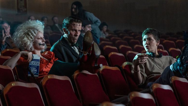 Jessie Buckley as The Bride sitting next to Christian Bale as Frank in a movie theater behind director Maggie Gyllenhaal on the set of The Bride!