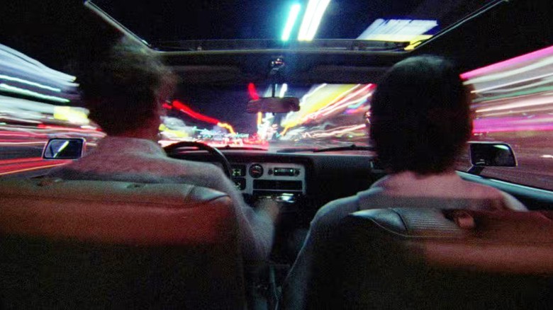 Two people in a car seen from behind in Koyaanisqati