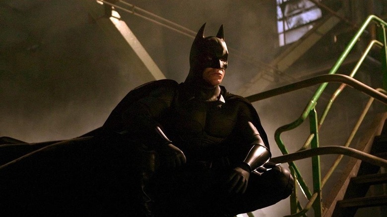 Christian Bale as Batman crouched on a beam in Batman Begins