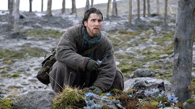 Christian Bale as Bruce Wayne wandering through the forest in Batman Begins