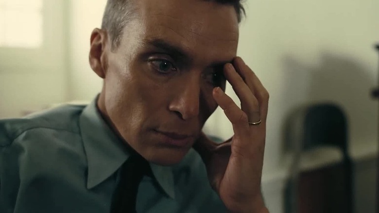 Cillian Murphy as J. Robert Oppenheimer with has hand on his face in Oppenheimer