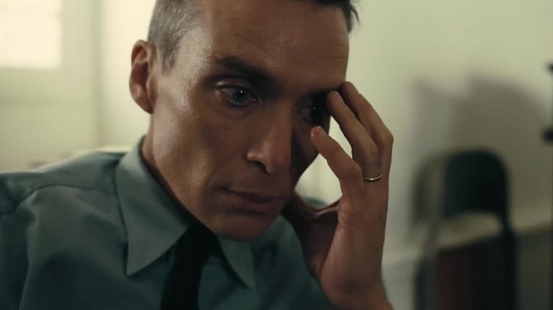Cillian Murphy as J. Robert Oppenheimer holding his face in Oppenheimer