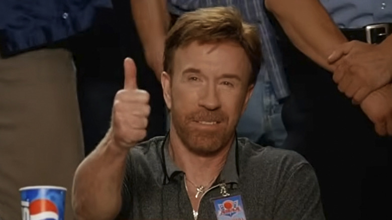 Chuck Norris as himself giving a thumb's up at a judge's table in front of a crowd in Dodgeball: A True Underdog Story