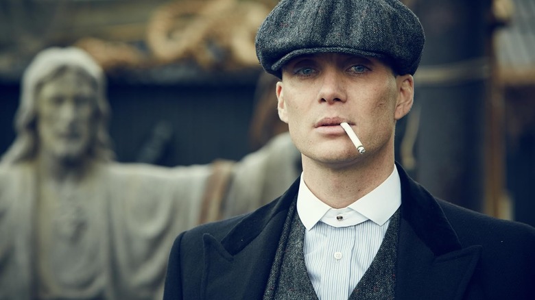 Tommy Shelby (Silian Murphy) smokes a cigarette in front of the statue of Jesus in the ambiguity
