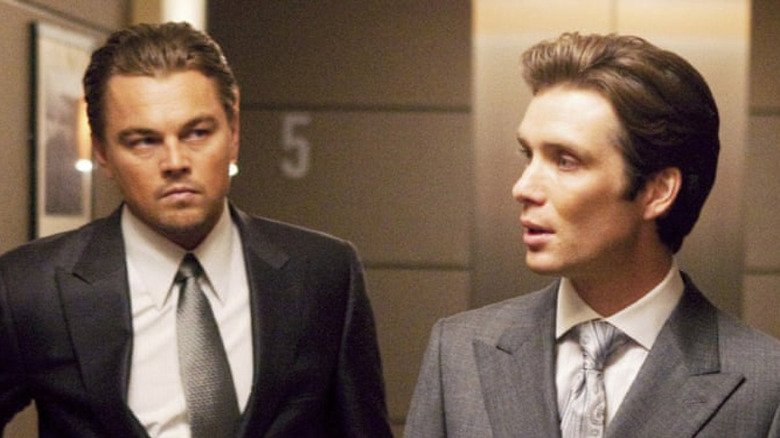 two men in suits, one on the left looking at the one on the right who is looking at something else
