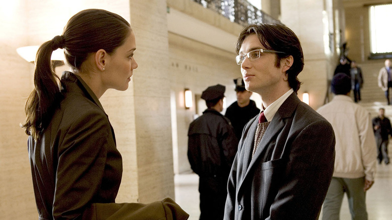 man in a suit and glasses talking to a woman with a ponytail