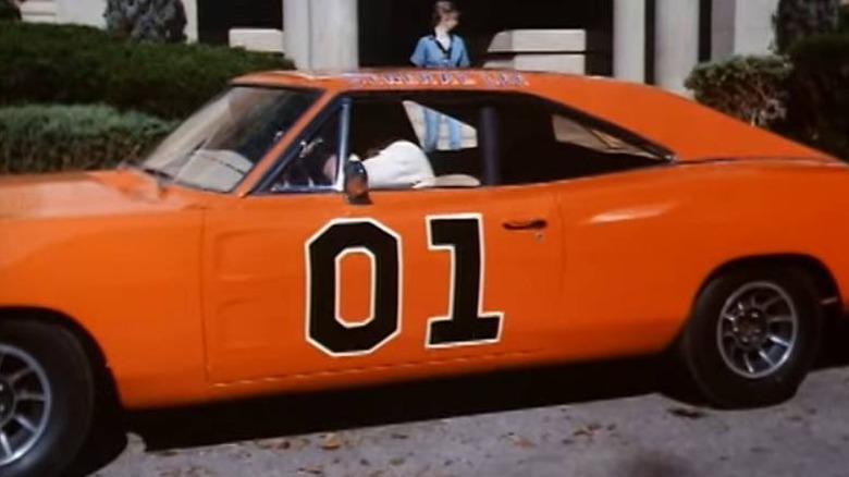 Bo (Luke Schneider) and Luke Duke (Tom Wopat) inside the General Lee on The Dukes of Hazzard