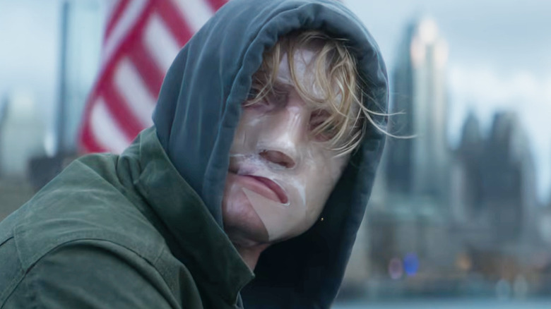 Tom Rhys Harries as Matt Hagen wearing a hoodie in front of a U.S. flag in Gotham in Clayface