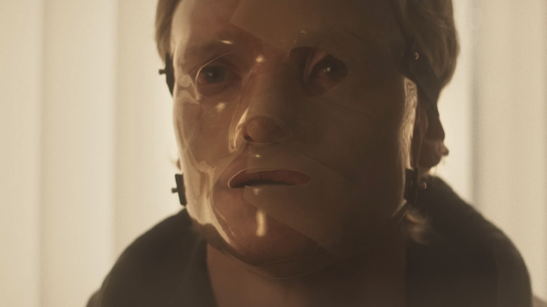 Tom Rhys Harries' Matt Hagen is seen wearing a mask in closeup in Clayface