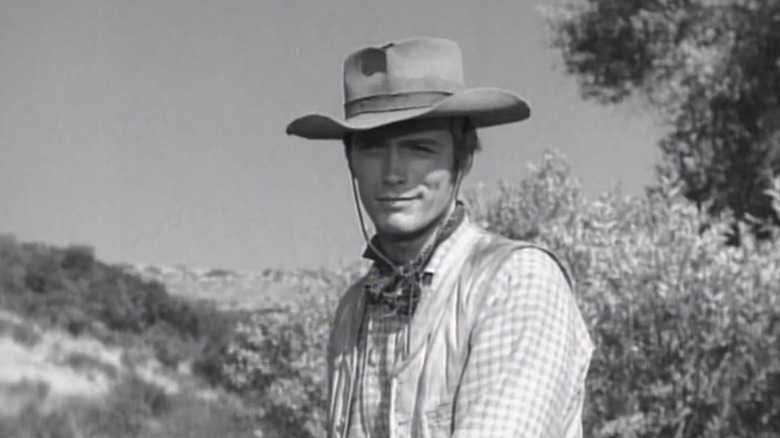 Clint Eastwood's Rowdy Yates smiles as he stands in a field in Rawhide