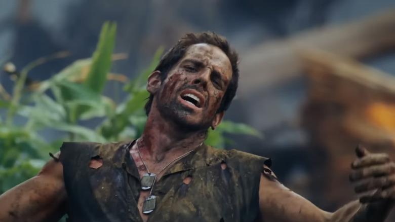 El Tug Speedman de Ben Stiller levanta los brazos mientras está parado en un bosque de Tropic Thunder.