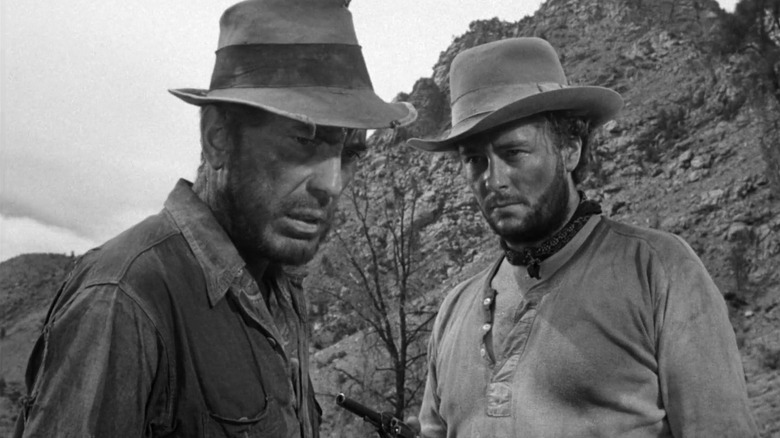 फ्रेड वाळवंट दरीत काहीतरी पाहत असताना बॉब सिएरा माद्रेच्या खजिन्यात त्याच्याकडे बंदूक दाखवतो