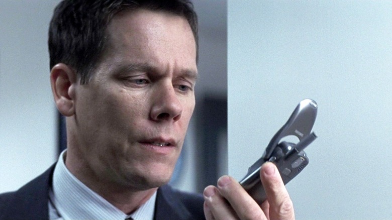 Detective Devine sosteniendo un teléfono de giro en Mystic River