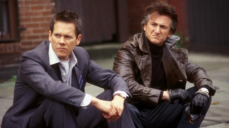 Detective Devine y Jimmy Markum sentados en una acera con un aspecto melancólico en Mystic River