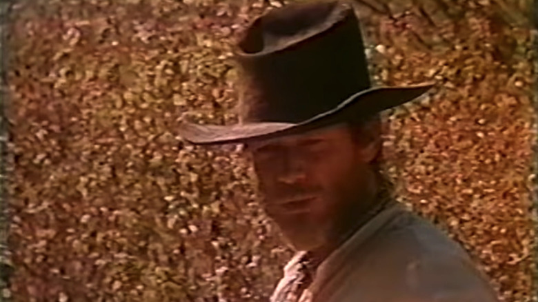 Michael Parks' Josey Wales stands in a field against a row of browning trees in The Return of Josey Wales