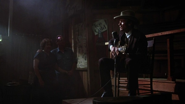 Clint Eastwood playing guitar and singing in a dive bar