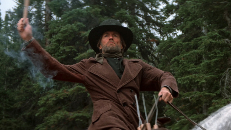 Clint Eastwood's Preacher prepares to throw dynamite as he rides a horse in Pale Rider