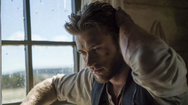 Jackson (Scott Eastwood) leans his arm against a bright window and rests his other hand on his head in a gesture of contemplation or stress in Diablo